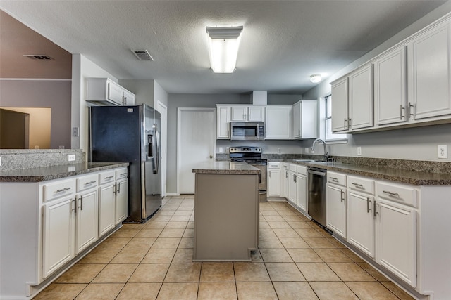 kitchen featuring sink, light tile patterned floors, white cabinetry, stainless steel appliances, and a center island