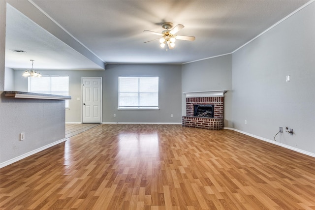 unfurnished living room featuring crown molding, a textured ceiling, a fireplace, ceiling fan with notable chandelier, and light wood-type flooring