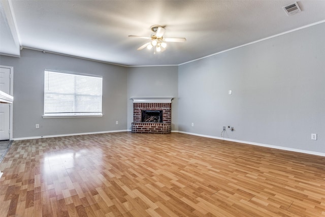 unfurnished living room featuring crown molding, a fireplace, light hardwood / wood-style floors, and ceiling fan