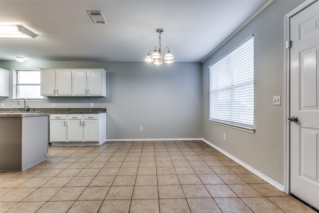 kitchen featuring sink, light tile patterned floors, white cabinetry, a notable chandelier, and decorative light fixtures