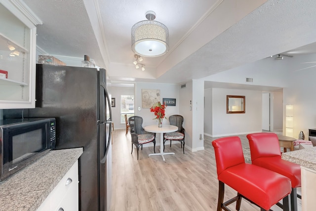 kitchen with a raised ceiling, light wood-type flooring, a textured ceiling, and white cabinetry