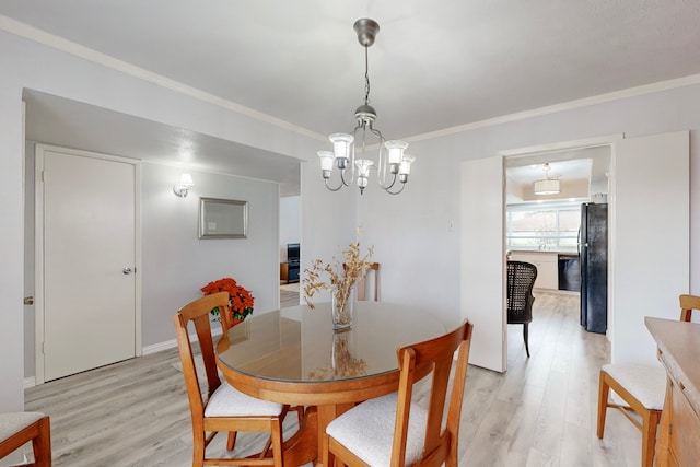 dining room with light hardwood / wood-style flooring, ornamental molding, and a notable chandelier