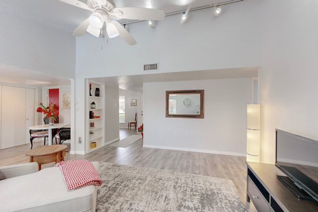 living room featuring ceiling fan, a towering ceiling, track lighting, and light hardwood / wood-style flooring