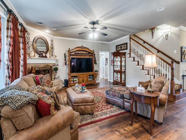 living room featuring a brick fireplace, ceiling fan, dark wood-type flooring, and ornamental molding