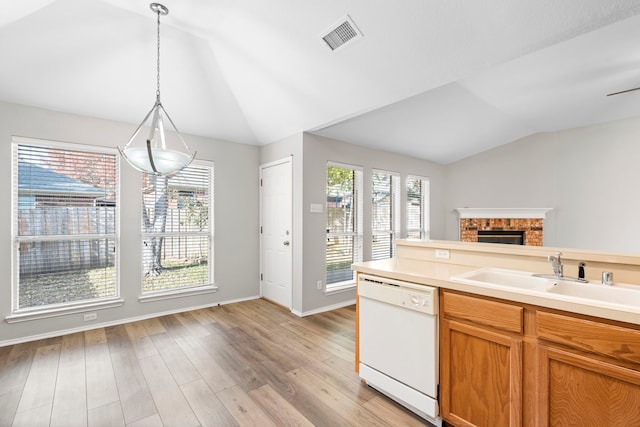 kitchen featuring vaulted ceiling, sink, decorative light fixtures, dishwasher, and light hardwood / wood-style floors