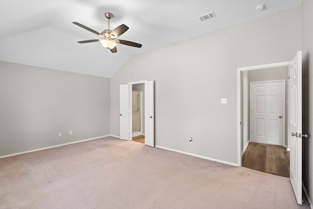 unfurnished bedroom featuring ceiling fan, light carpet, and vaulted ceiling