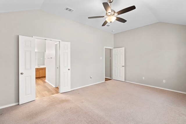 unfurnished bedroom with connected bathroom, ceiling fan, light colored carpet, and lofted ceiling