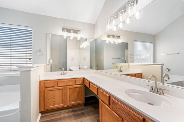 bathroom with a wealth of natural light, vanity, wood-type flooring, and vaulted ceiling