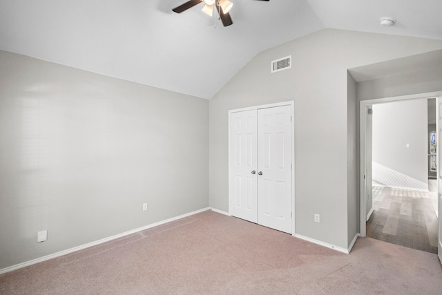 unfurnished bedroom featuring light carpet, a closet, ceiling fan, and lofted ceiling