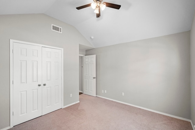 unfurnished bedroom with ceiling fan, a closet, light colored carpet, and vaulted ceiling