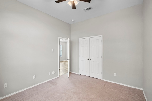 unfurnished bedroom featuring ceiling fan, a closet, and light colored carpet