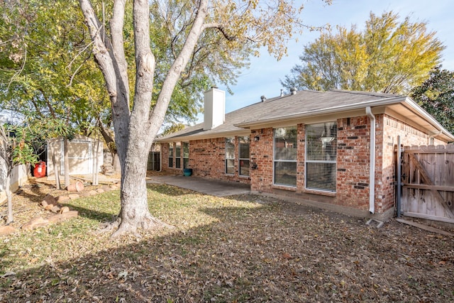 rear view of property with a patio and a shed