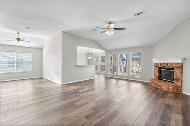 unfurnished living room with a fireplace, wood-type flooring, vaulted ceiling, and ceiling fan