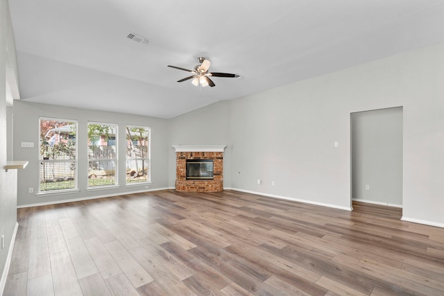 unfurnished living room with vaulted ceiling, light hardwood / wood-style flooring, a brick fireplace, and ceiling fan