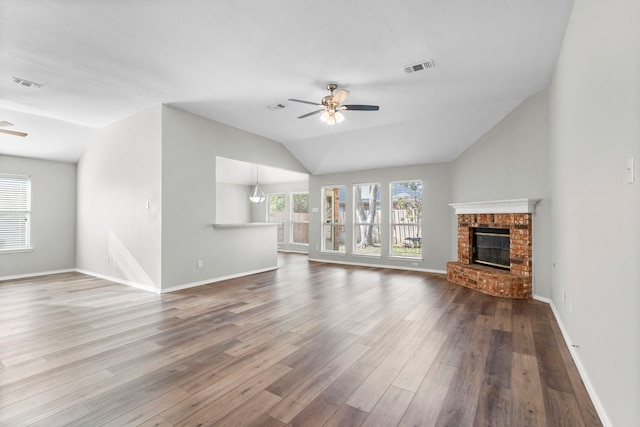 unfurnished living room with wood-type flooring, a brick fireplace, ceiling fan, and lofted ceiling