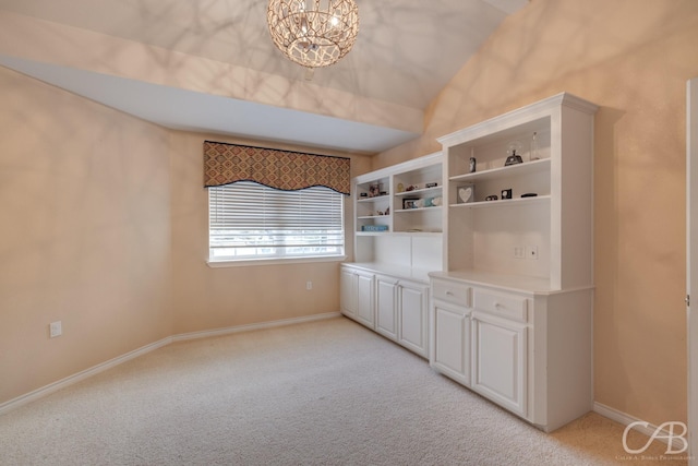 spare room with light carpet, vaulted ceiling, and a notable chandelier