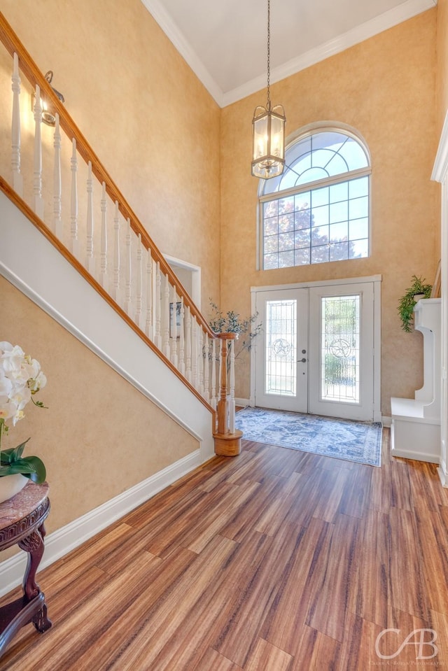 entrance foyer featuring crown molding, french doors, wood-type flooring, and a high ceiling