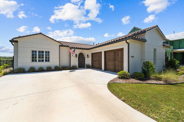 mediterranean / spanish home featuring a garage and a front lawn