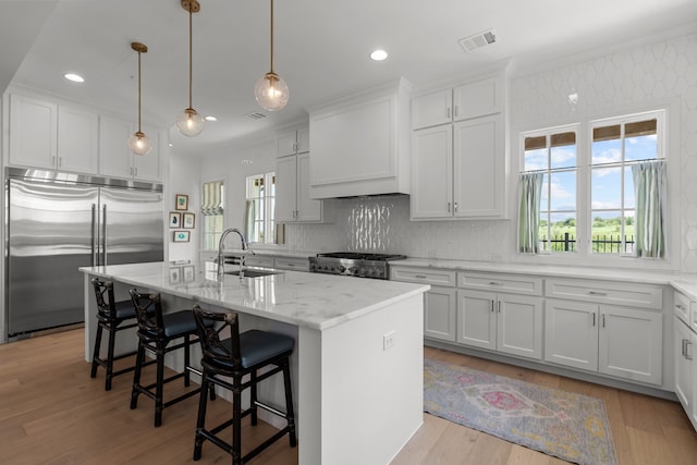 kitchen with a center island with sink, sink, light hardwood / wood-style flooring, appliances with stainless steel finishes, and white cabinetry