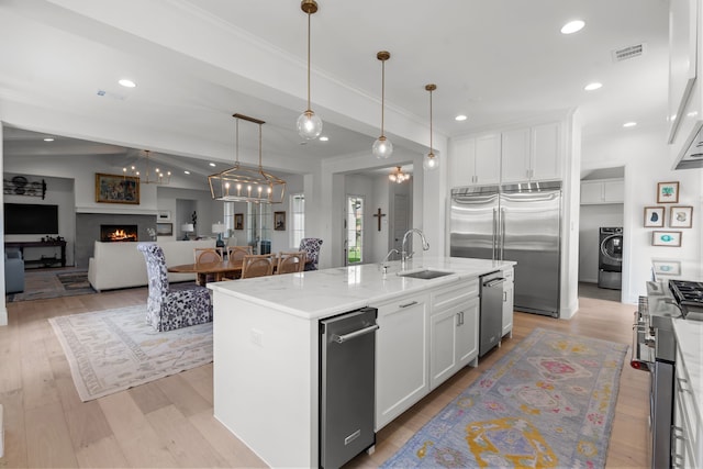 kitchen featuring white cabinets, sink, vaulted ceiling, an island with sink, and stainless steel appliances