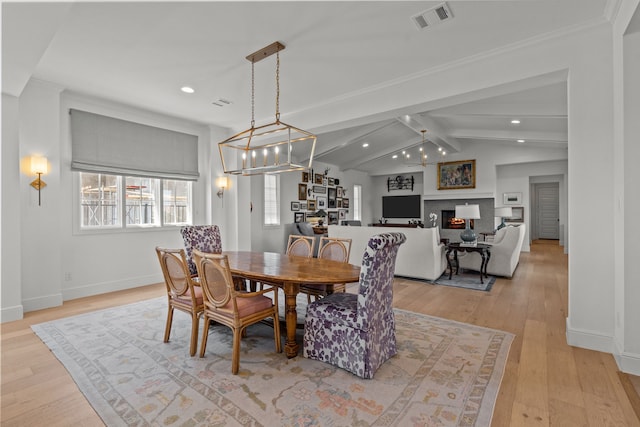 dining space featuring lofted ceiling with beams, light hardwood / wood-style flooring, and a notable chandelier