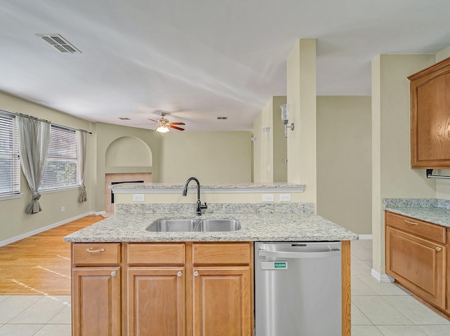 kitchen with sink, light tile patterned floors, ceiling fan, light stone countertops, and stainless steel dishwasher