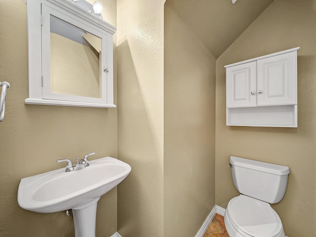 bathroom featuring vaulted ceiling, sink, tile patterned floors, and toilet