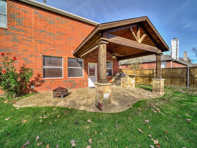 rear view of house featuring a fire pit, a patio area, and a lawn