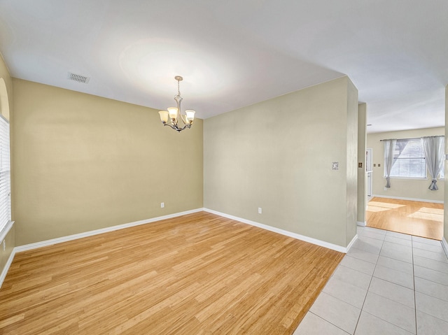 empty room featuring a chandelier and light hardwood / wood-style flooring