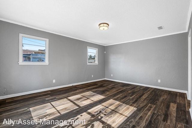 spare room featuring dark hardwood / wood-style flooring, crown molding, and a healthy amount of sunlight