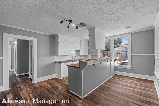 kitchen with white cabinets, wood counters, kitchen peninsula, and dark wood-type flooring