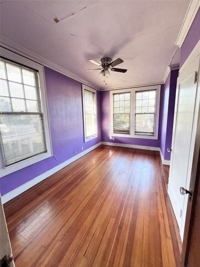 empty room with hardwood / wood-style floors, ornamental molding, and ceiling fan