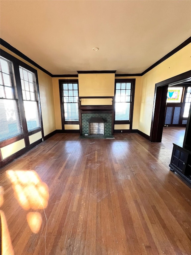 unfurnished living room with a brick fireplace, ornamental molding, and hardwood / wood-style flooring