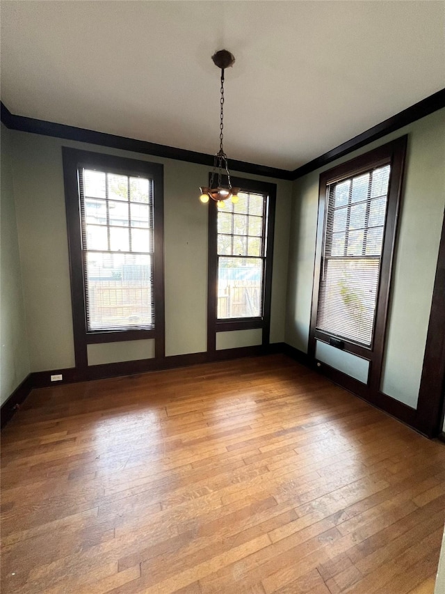 unfurnished dining area featuring light wood-type flooring, an inviting chandelier, and a wealth of natural light