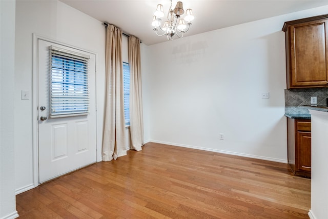 unfurnished dining area featuring light hardwood / wood-style flooring and a notable chandelier