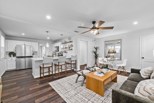 living room featuring ceiling fan and dark hardwood / wood-style floors