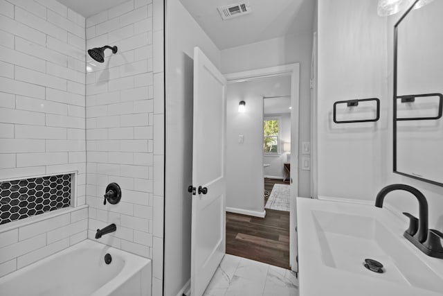 bathroom with vanity, wood-type flooring, and tiled shower / bath