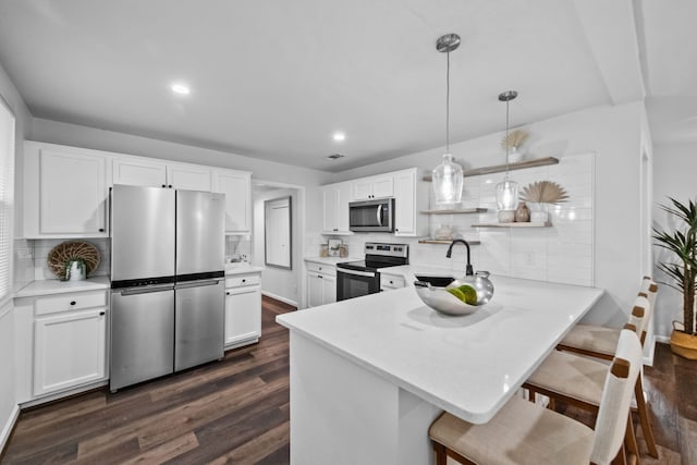 kitchen with white cabinets, decorative backsplash, dark hardwood / wood-style flooring, and stainless steel appliances