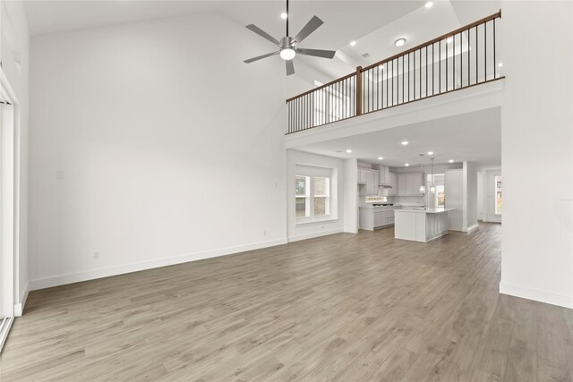1385 Melcer St, Frisco, TX 75036 - unfurnished living room with baseboards, high vaulted ceiling, light wood-style flooring, and a ceiling fan