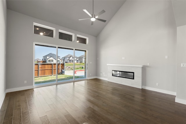 1590 Marburg Ln, Frisco, TX 75036 - unfurnished living room with high vaulted ceiling, wood finished floors, a tiled fireplace, ceiling fan, and baseboards
