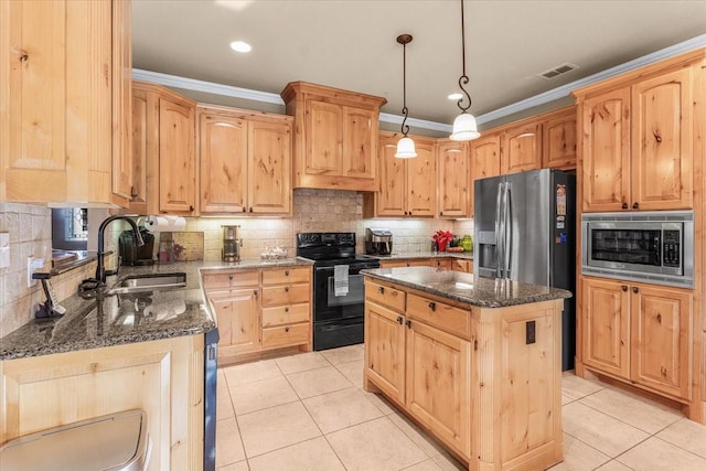 kitchen with appliances with stainless steel finishes, a kitchen island, dark stone countertops, and sink