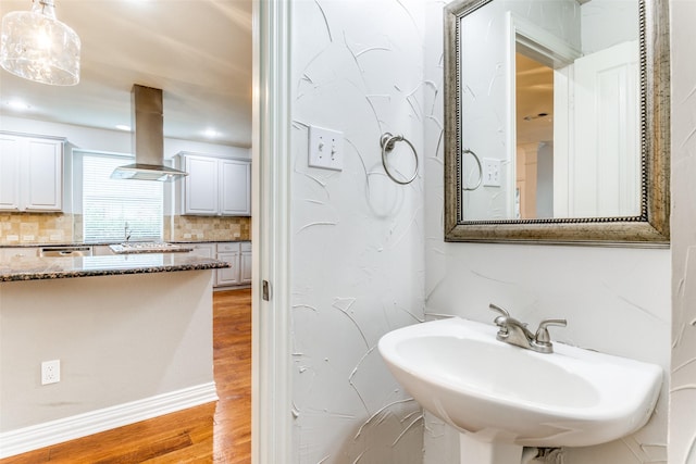 bathroom with wood-type flooring, sink, and decorative backsplash