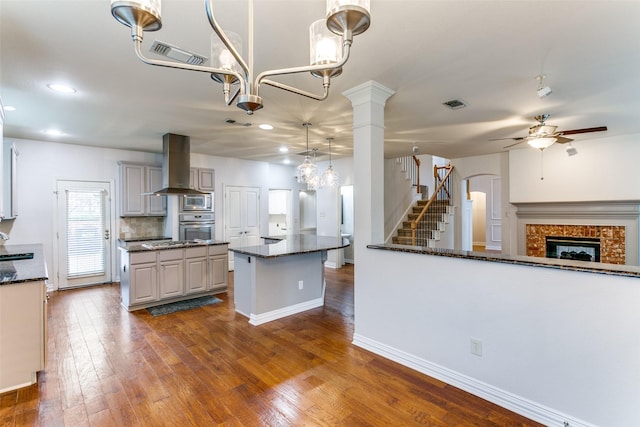 kitchen with stainless steel appliances, island exhaust hood, dark stone countertops, and pendant lighting