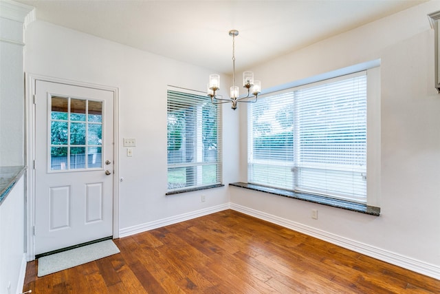 unfurnished dining area with hardwood / wood-style flooring and a chandelier