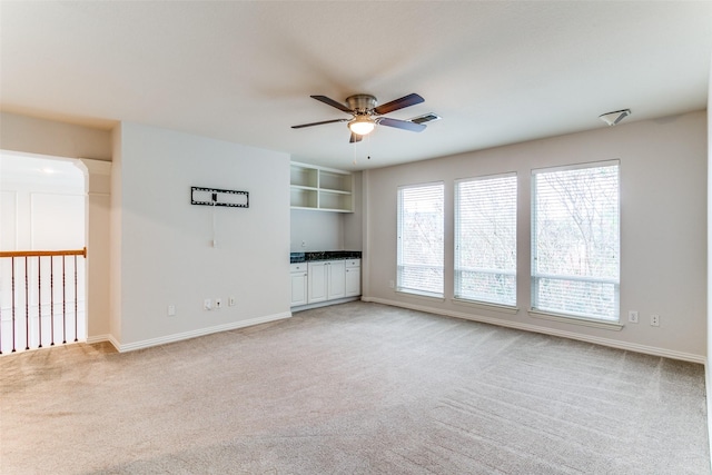 unfurnished living room featuring light colored carpet and ceiling fan