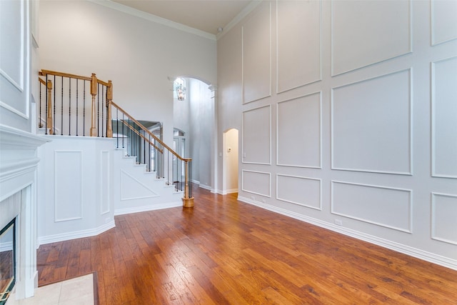 entrance foyer featuring a fireplace, crown molding, and wood-type flooring