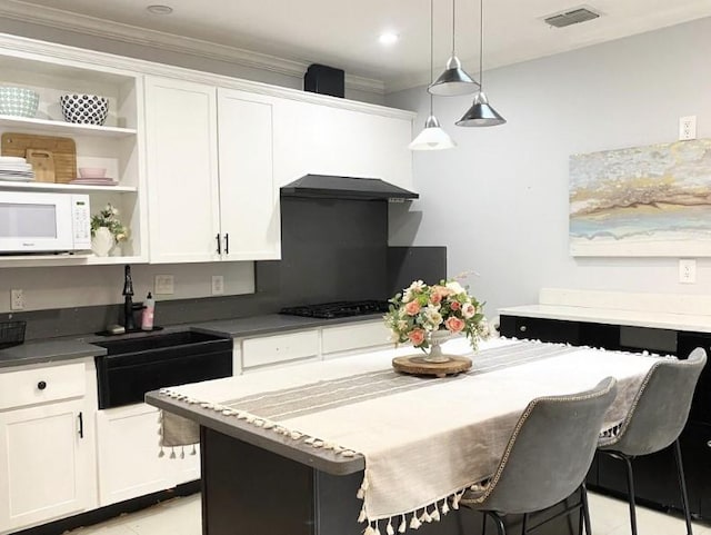 kitchen with a breakfast bar area, white cabinets, and hanging light fixtures