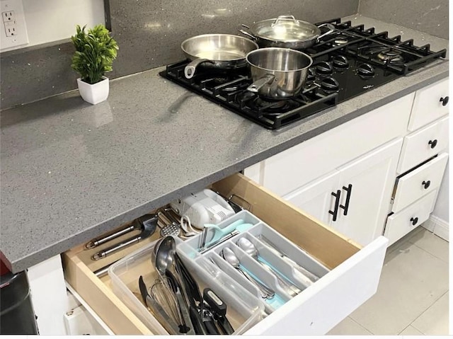 interior details with white cabinetry, black gas cooktop, and tasteful backsplash