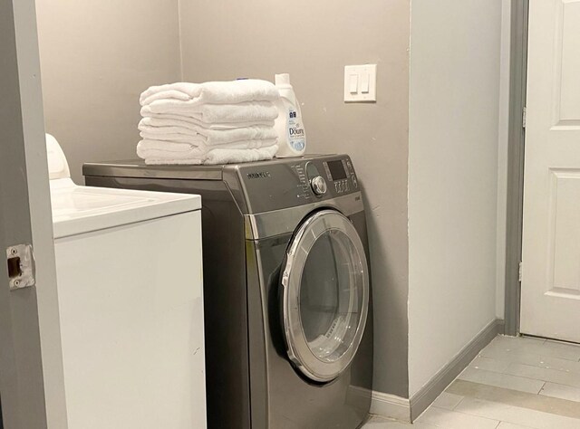 laundry room with light tile patterned floors and washing machine and clothes dryer