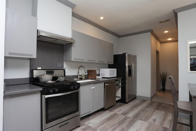 kitchen with sink, stainless steel appliances, gray cabinets, and wall chimney range hood